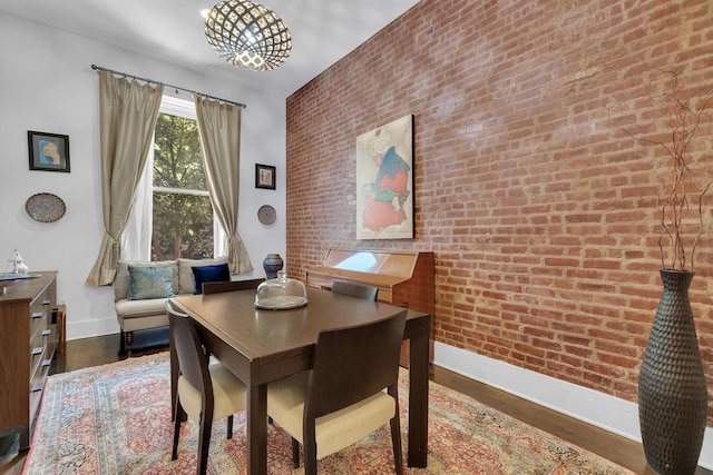 dining area featuring baseboards, brick wall, and wood finished floors