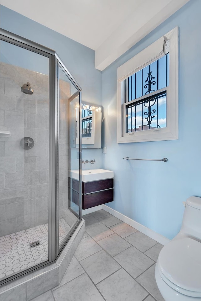 bathroom with vanity, toilet, a stall shower, baseboards, and tile patterned flooring