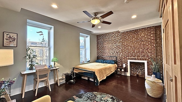 bedroom with brick wall, recessed lighting, wood finished floors, and baseboards