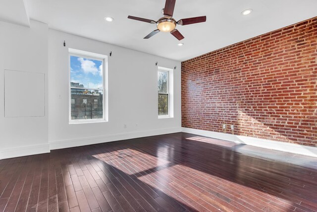 unfurnished room with hardwood / wood-style floors, baseboards, brick wall, recessed lighting, and a ceiling fan