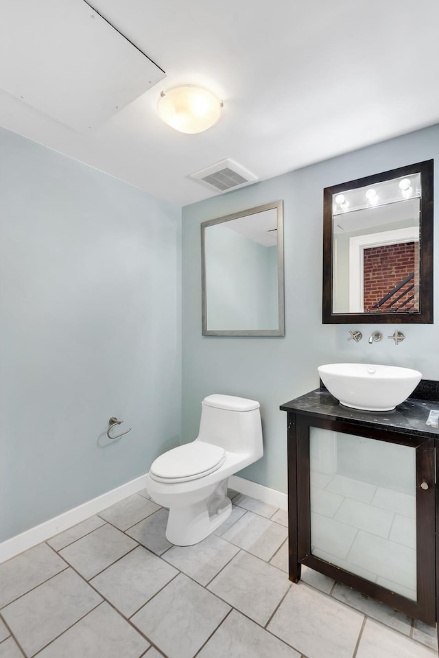 bathroom with toilet, vanity, visible vents, and baseboards