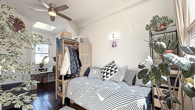 bedroom featuring a skylight, a closet, ceiling fan, beamed ceiling, and hardwood / wood-style flooring