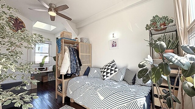 bedroom with lofted ceiling with skylight, ceiling fan, a closet, and wood-type flooring