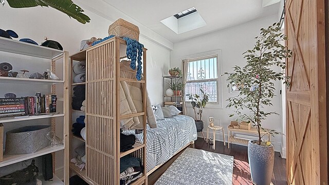 bedroom with baseboards, a skylight, and wood finished floors