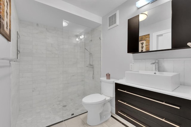 bathroom featuring tile patterned floors, toilet, tiled shower, and vanity