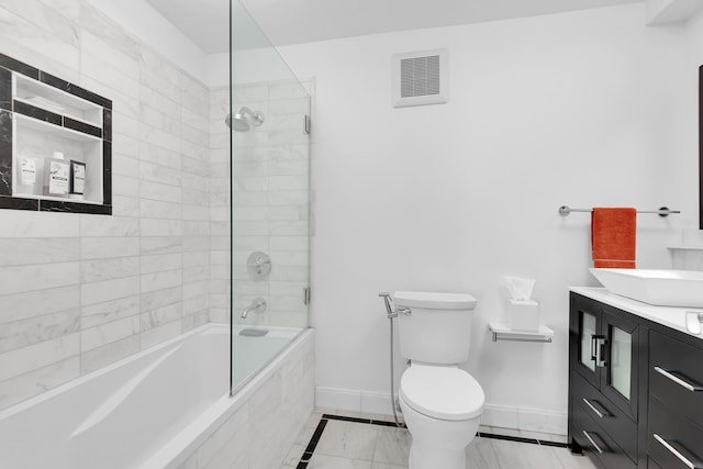 bathroom featuring baseboards, visible vents, toilet, tiled shower / bath combo, and vanity