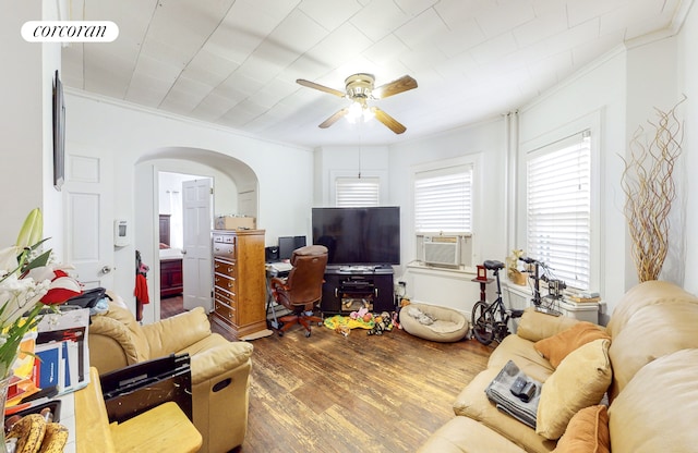 living room with crown molding, a ceiling fan, visible vents, arched walkways, and wood finished floors