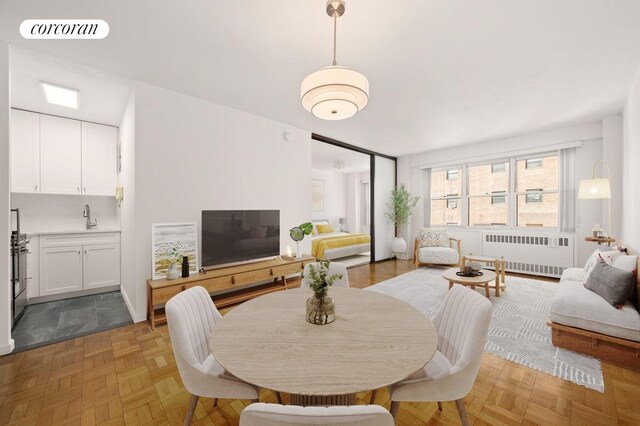 dining room with radiator, sink, and light parquet floors