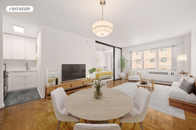 dining area with radiator, sink, and light parquet floors