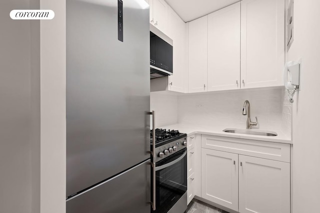 kitchen featuring tasteful backsplash, appliances with stainless steel finishes, sink, and white cabinets