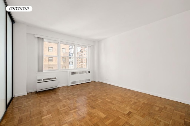 spare room with radiator heating unit, heating unit, and light parquet floors