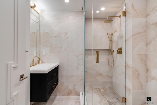 bathroom featuring vanity, a marble finish shower, tile walls, and recessed lighting