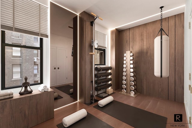 exercise room with wood walls and wood finished floors