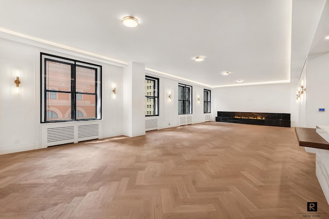 unfurnished living room with a fireplace and radiator heating unit