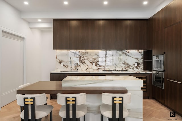 kitchen featuring modern cabinets, a sink, dark brown cabinets, and recessed lighting