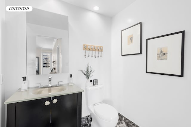 bathroom featuring toilet, ornamental molding, and vanity