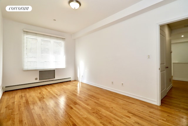 empty room featuring a baseboard heating unit, light wood-style floors, visible vents, and baseboards