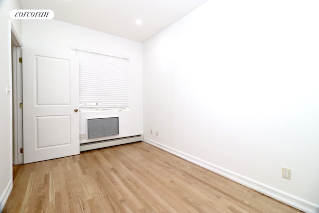 empty room featuring light wood-type flooring, a baseboard heating unit, baseboards, and visible vents