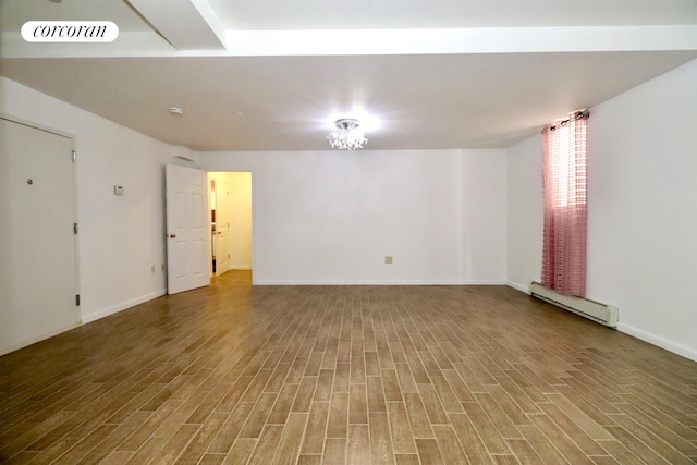 unfurnished room with baseboard heating, baseboards, visible vents, and wood finished floors