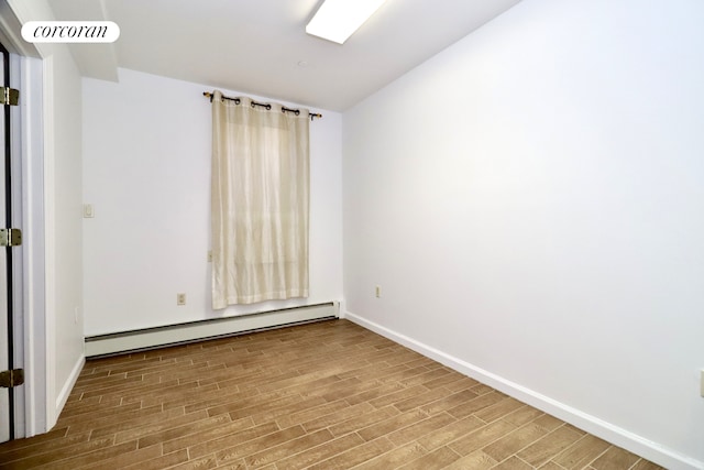 empty room featuring a baseboard heating unit, baseboards, visible vents, and wood finished floors