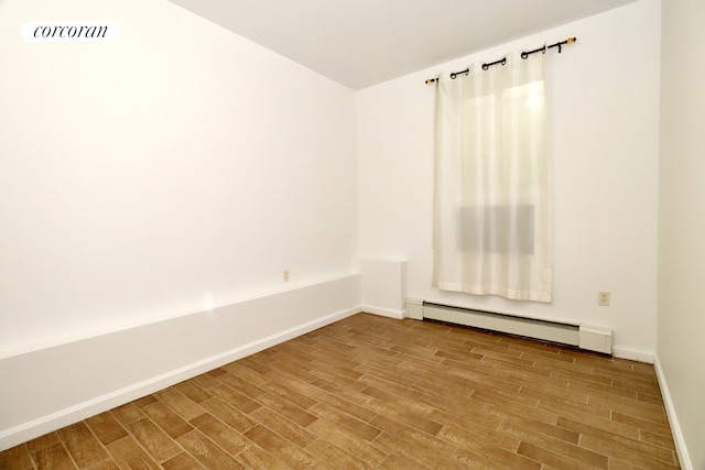 unfurnished room featuring visible vents, wood finished floors, baseboards, and a baseboard radiator