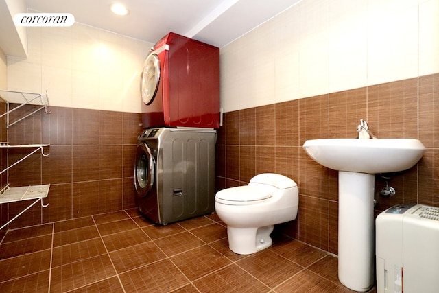 bathroom featuring visible vents, stacked washer and dryer, tile walls, toilet, and tile patterned floors