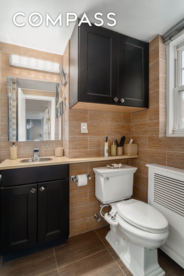 bathroom featuring vanity, tile walls, toilet, and tasteful backsplash