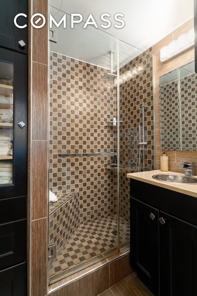 full bath featuring tile walls, a stall shower, and vanity