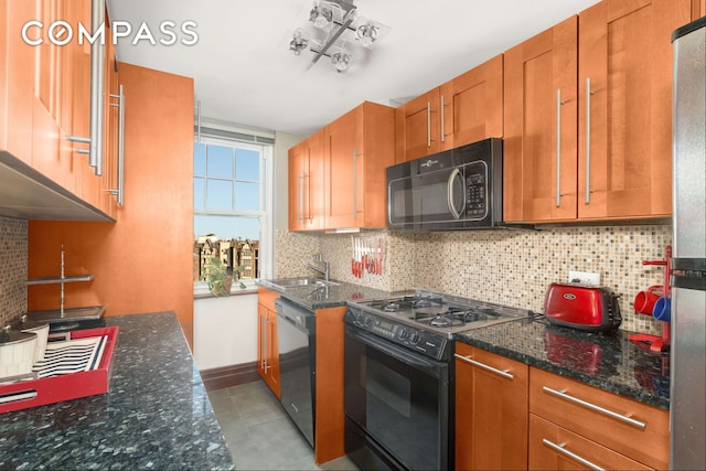 kitchen with dark stone countertops, brown cabinetry, a sink, black appliances, and tasteful backsplash