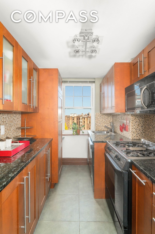 kitchen with brown cabinetry, backsplash, black appliances, and a sink