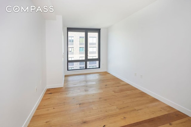 empty room with light wood-type flooring and baseboards