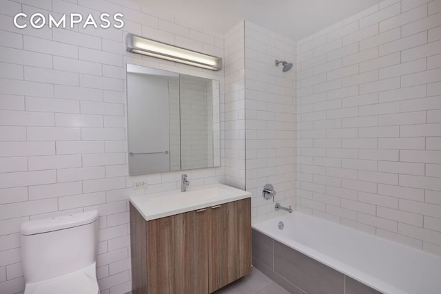 full bathroom featuring toilet, tiled shower / bath, tile walls, and vanity