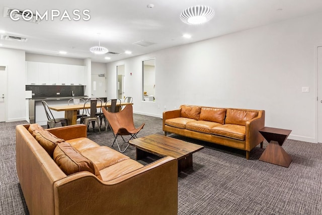 living room with visible vents, dark carpet, and baseboards