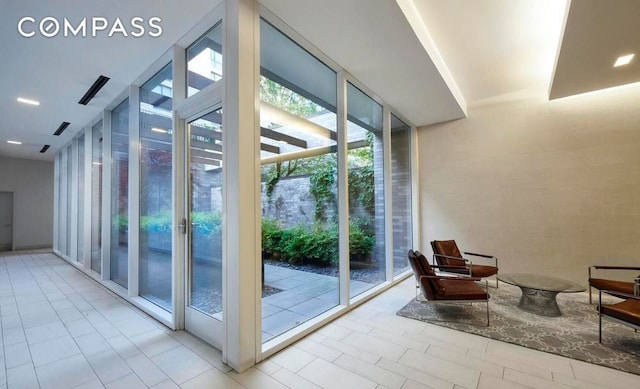 doorway to outside with expansive windows, light tile patterned floors, and visible vents