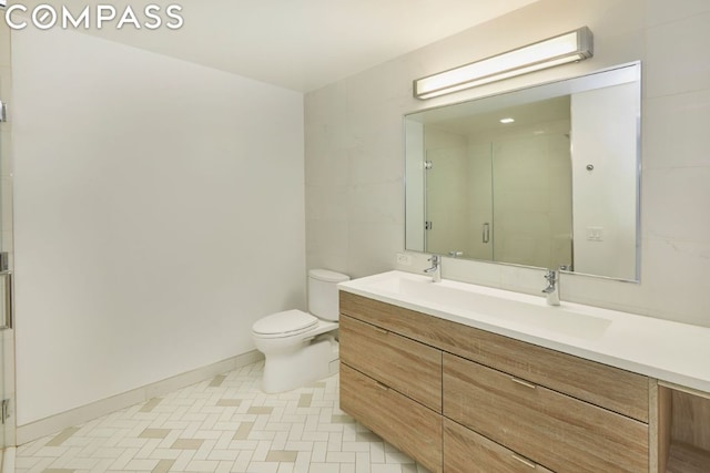 bathroom featuring a shower with shower door, toilet, and vanity