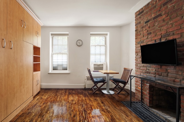 unfurnished dining area with cooling unit, a brick fireplace, dark wood-type flooring, and radiator heating unit