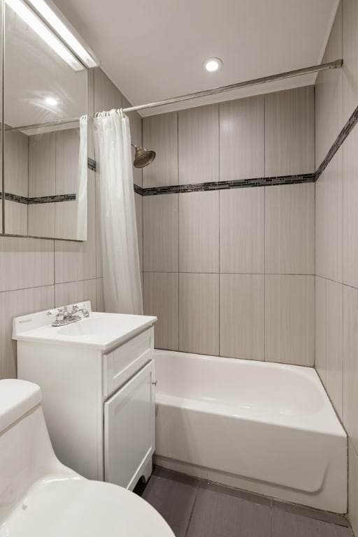 full bathroom with tile patterned floors, toilet, tile walls, vanity, and shower / bathtub combination with curtain