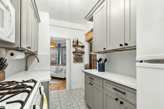 215 E 79th St Unit 6F, New York City, NY 10075 - kitchen featuring white appliances, gray cabinets, decorative backsplash, and light stone countertops