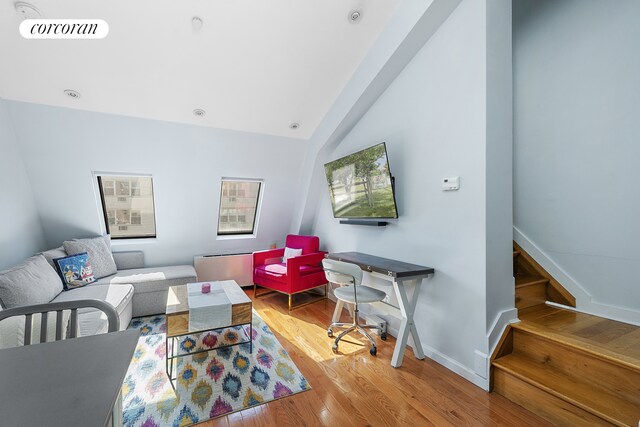 living room featuring lofted ceiling and light hardwood / wood-style flooring