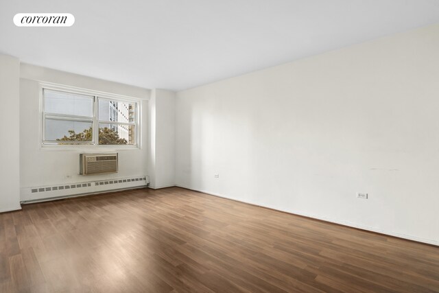 empty room with wood finished floors, baseboard heating, a wall mounted AC, and visible vents