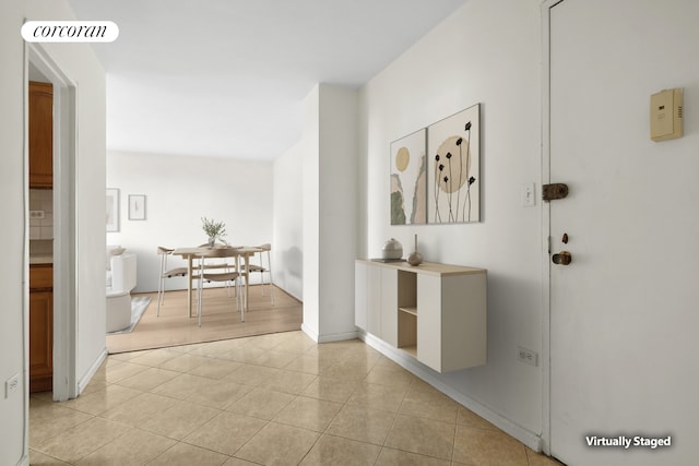 hallway with light tile patterned floors, visible vents, and baseboards
