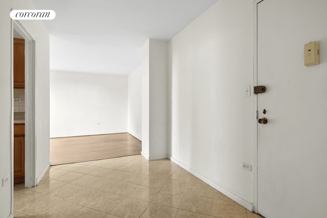 hallway with baseboards, visible vents, and light tile patterned floors