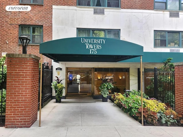 entrance to property featuring fence and brick siding