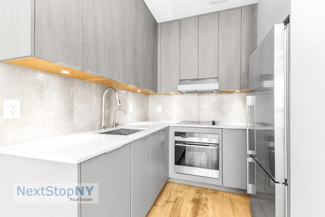 kitchen with stainless steel appliances, tasteful backsplash, sink, and gray cabinetry