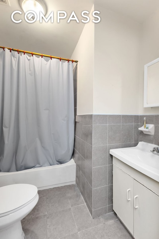 bathroom featuring shower / tub combo with curtain, tile walls, toilet, vanity, and tile patterned flooring