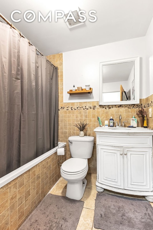 bathroom with toilet, vanity, tile walls, tile patterned floors, and shower / bath combination with curtain