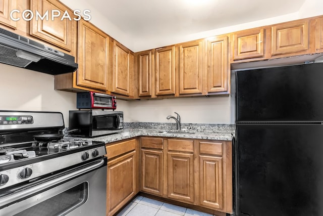 kitchen with light stone counters, light tile patterned flooring, under cabinet range hood, stainless steel appliances, and a sink