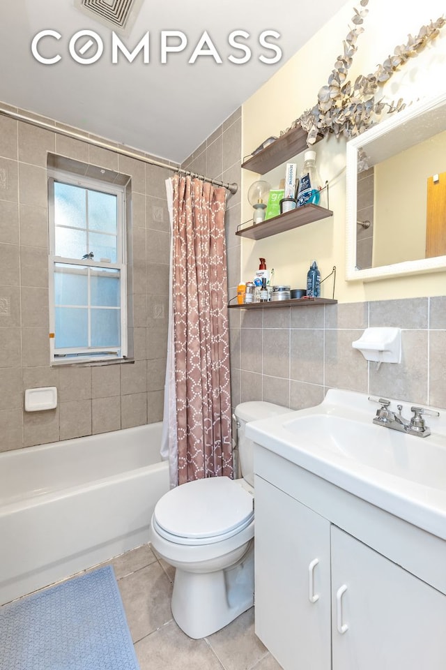 full bath featuring shower / bath combo, toilet, tile patterned floors, vanity, and tile walls