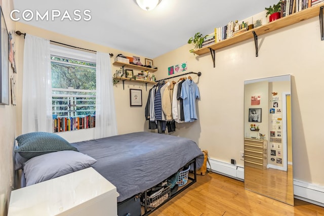 bedroom featuring a baseboard heating unit, baseboard heating, and wood finished floors