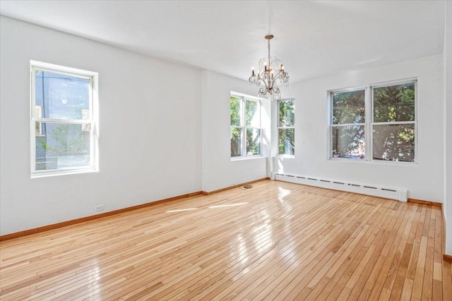 spare room with baseboard heating, a chandelier, and light hardwood / wood-style flooring